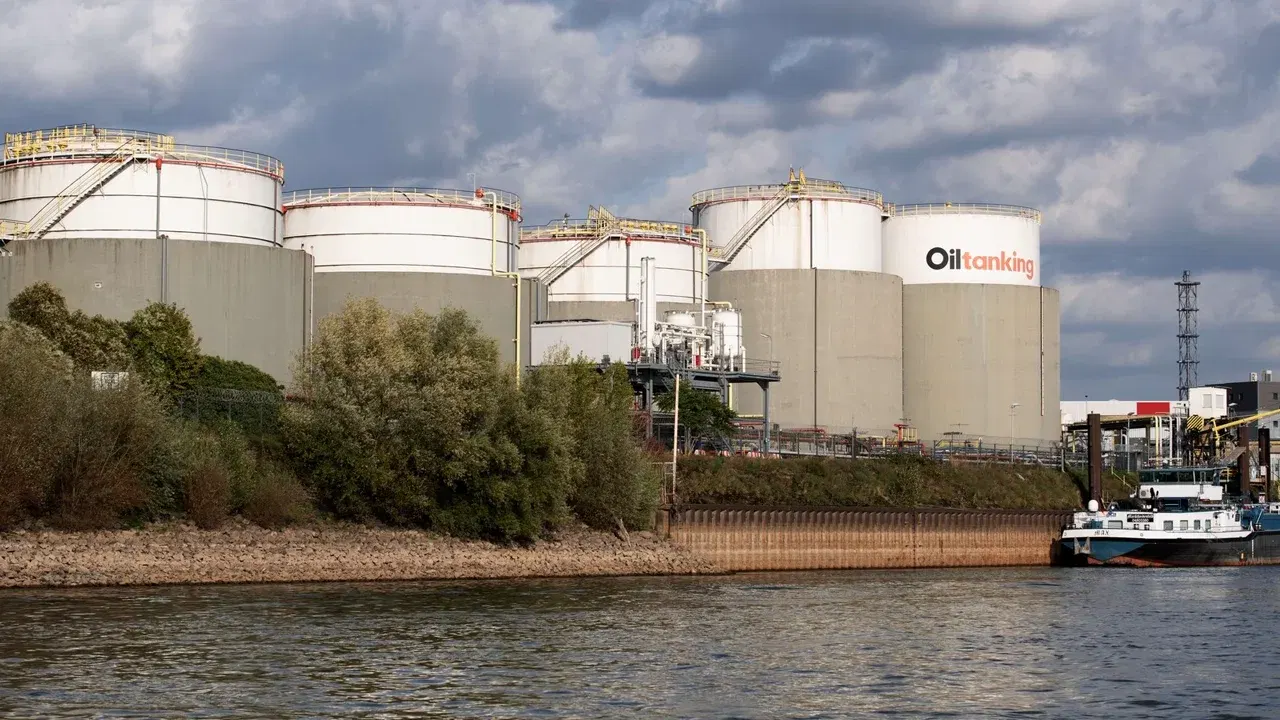 Rezervoare industriale pentru produse petroliere, lângă un cheu, văzute de pe apă.