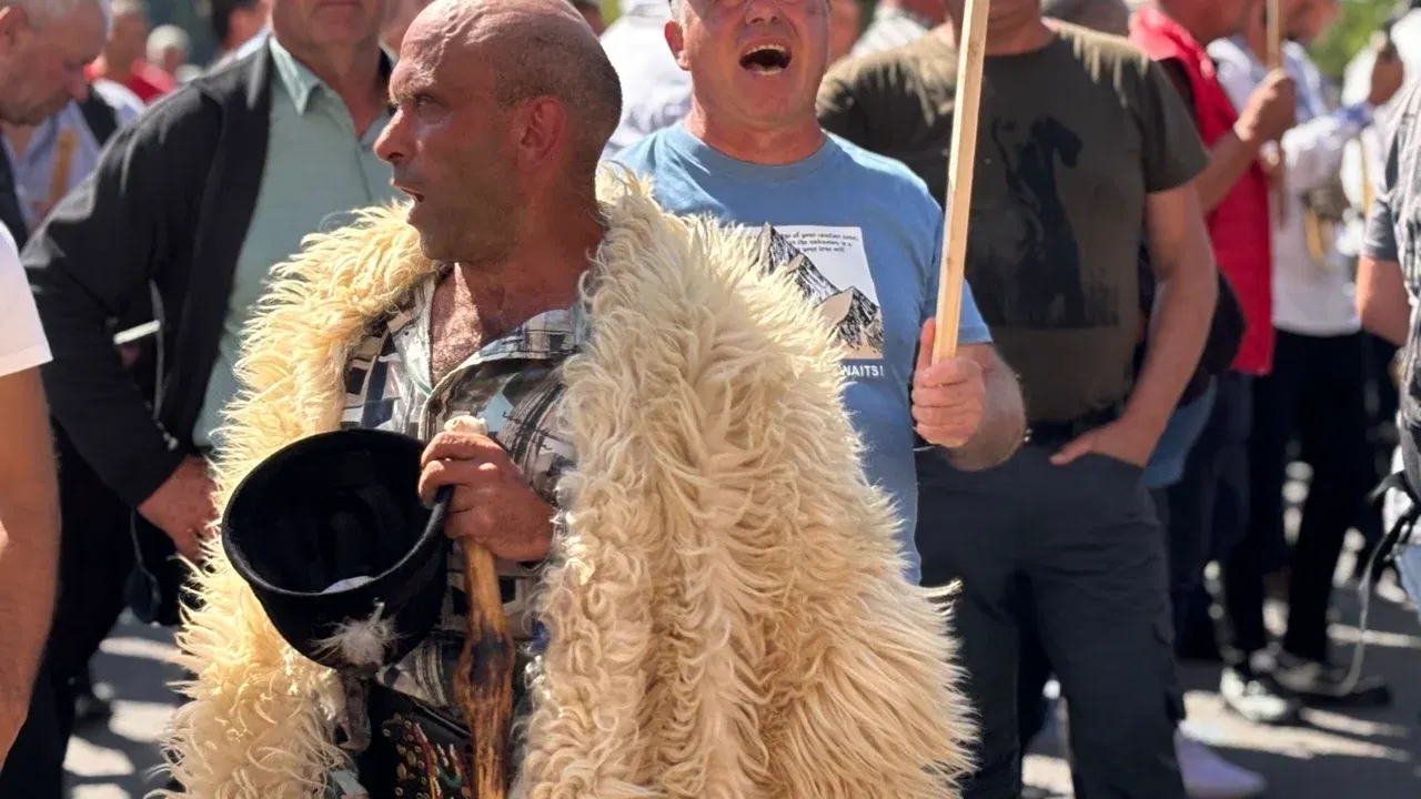 Crescător de oi la un protest al fermierilor, ținând un baston și un clopot