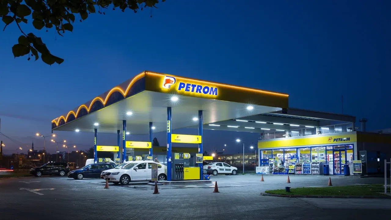 Stație Petrom luminată seara, cu autoturisme la pompe