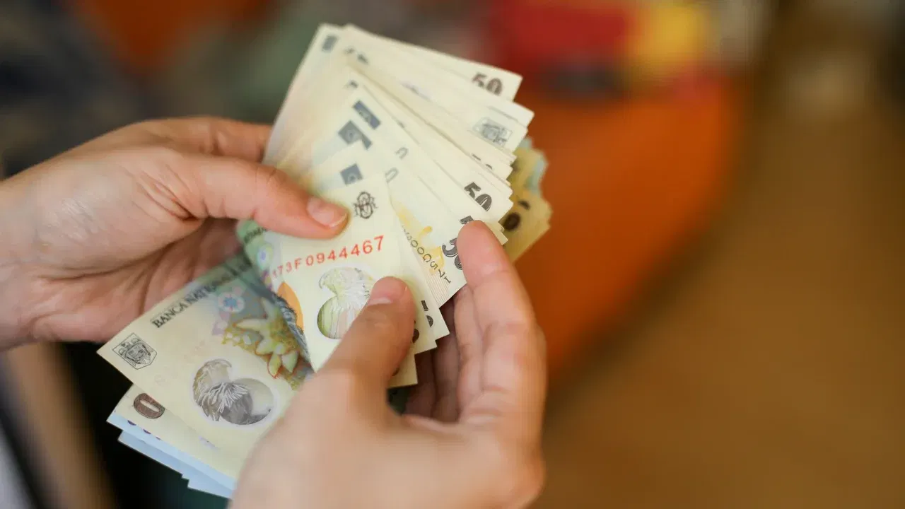 Mâini care numără bancnote românești, imagine ilustrativă pentru plata pensiilor