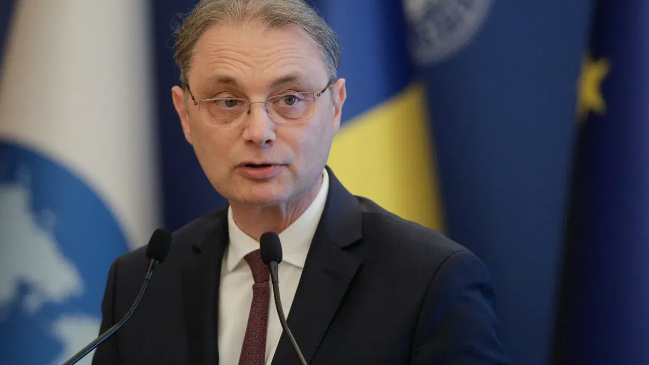 Luca Niculescu vorbește la un pupitru, cu drapelul României în fundal