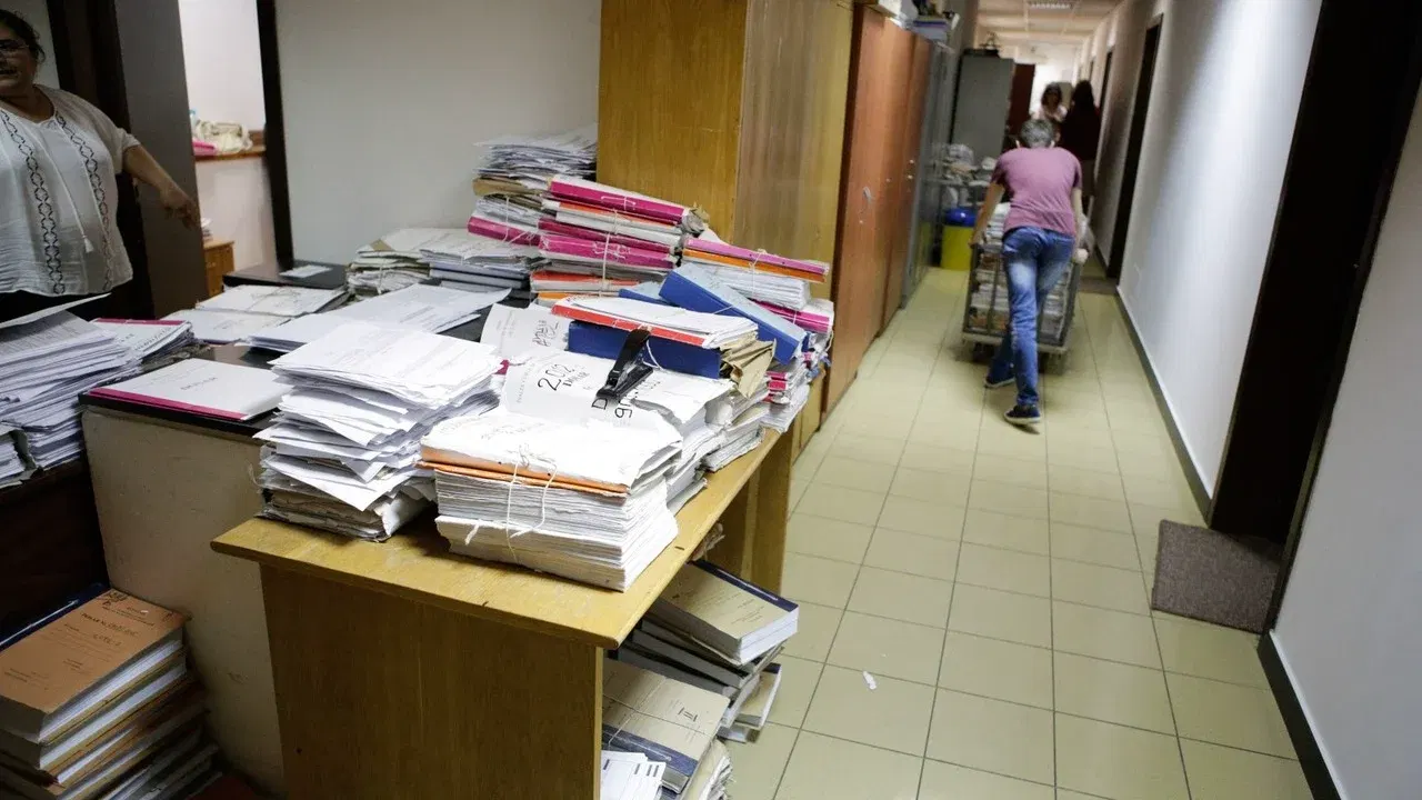 Dosare stivuite pe mesele unei instanțe, într-un coridor
