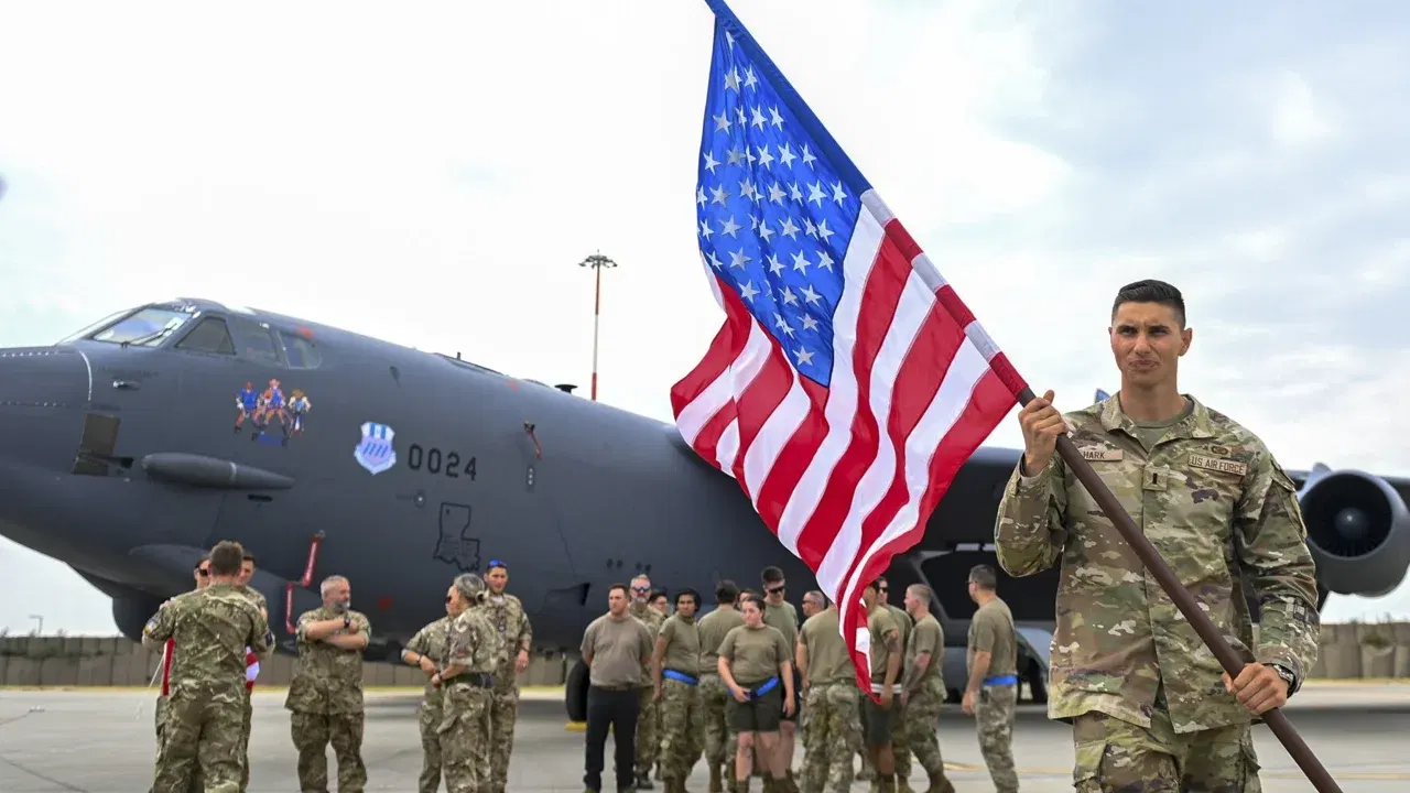 Militari americani în fața unei aeronave de transport, cu drapelul SUA