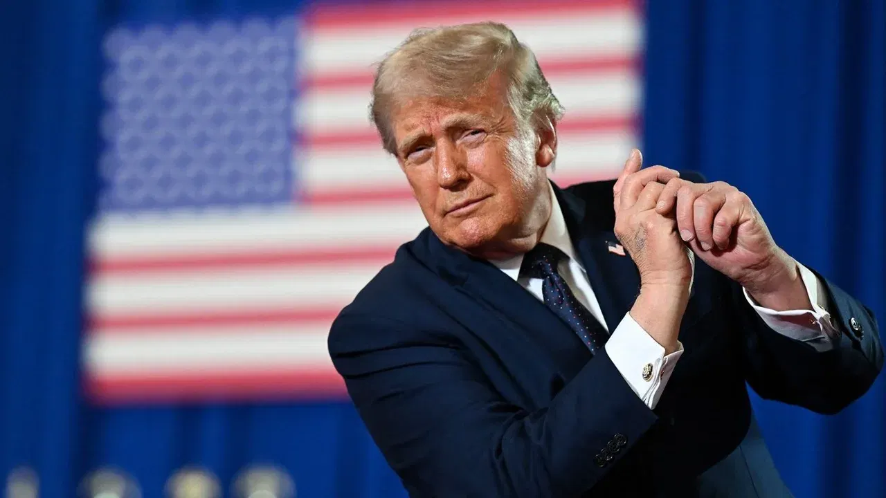 Donald Trump aplaudă în fața unui steag american