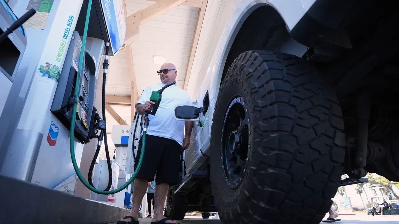 Un șofer alimentează cu carburant un camion la o benzinărie