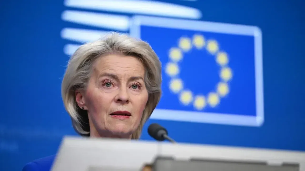 Ursula von der Leyen la un pupitru, cu steagul Uniunii Europene în fundal