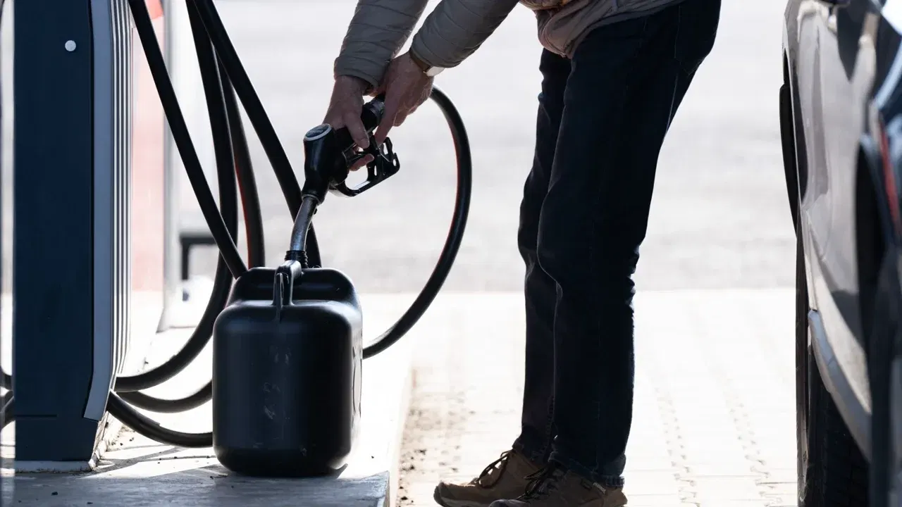Un șofer alimentează un recipient cu carburant la o benzinărie, imagine ilustrativă